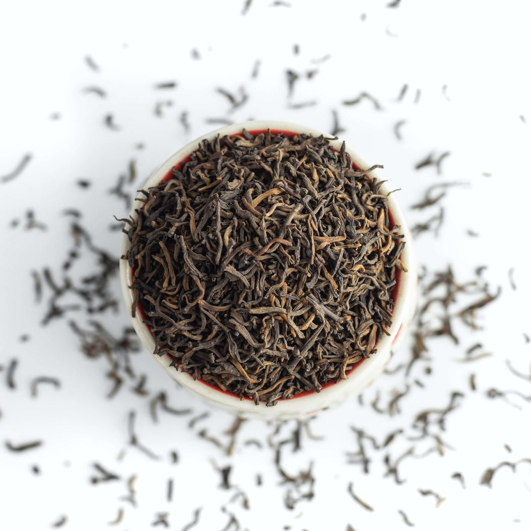 tasse remplie de feuilles de thé vert en vrac.